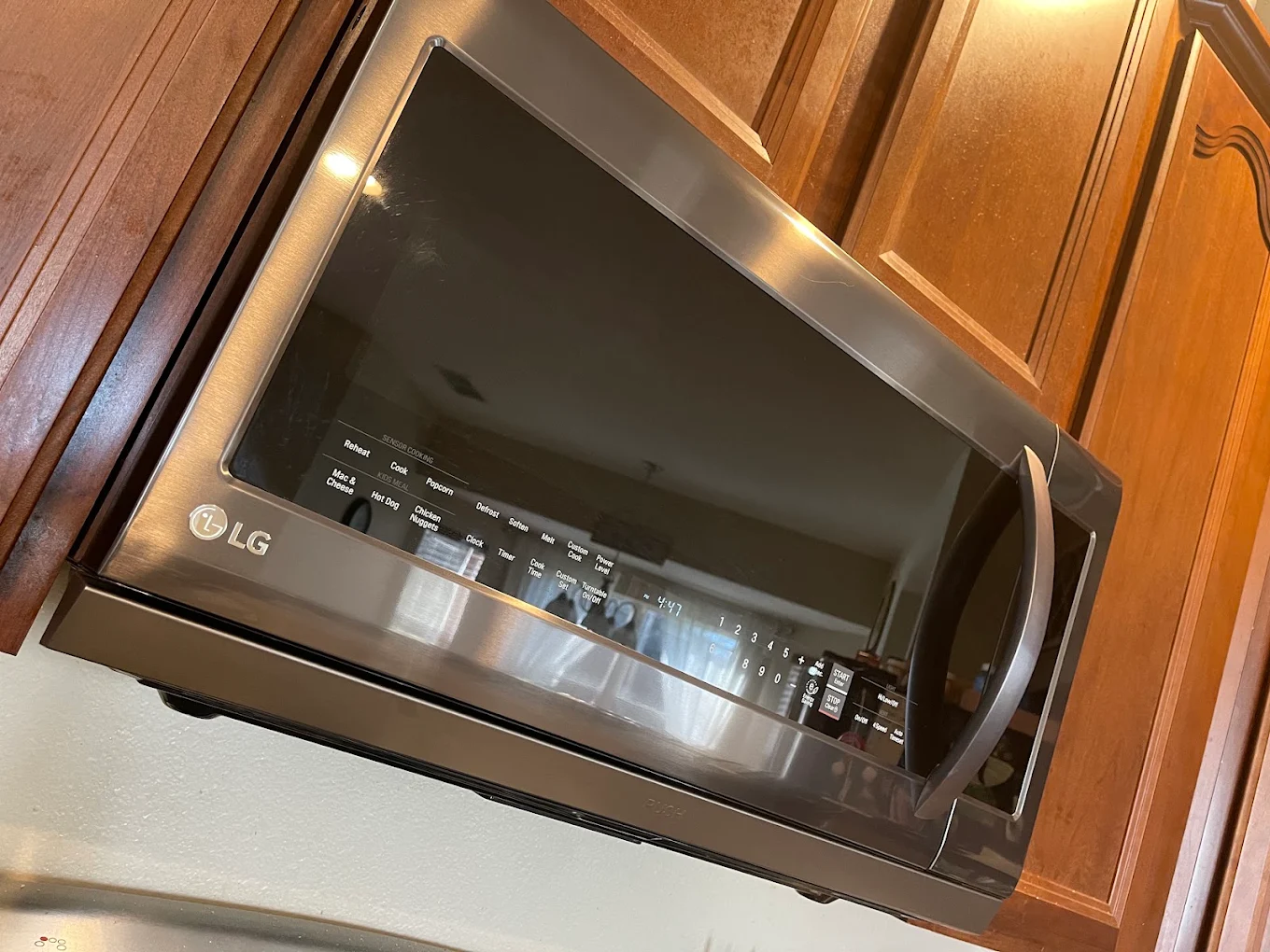 Microondas LG de acero inoxidable instalado debajo de gabinetes de madera